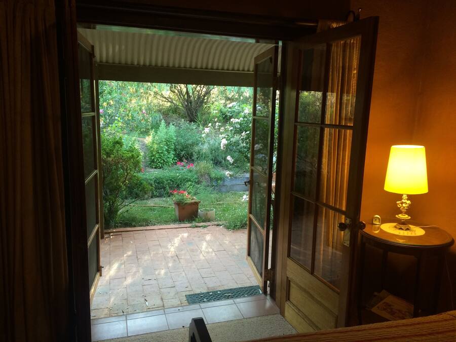 Puerta abierta que da a un jardín con una planta en maceta y una lámpara de mesa.