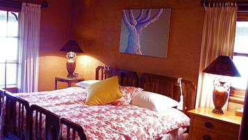 Een slaapkamer met een bed, twee nachtkastjes, een stoel, een schilderij aan de muur en een raam met gordijnen.