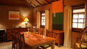 A dining area with a wooden table, chairs, a chandelier, a lamp, and a green accent wall.