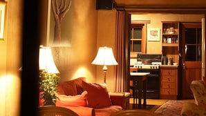 Un salon chaleureux avec un plafond en bois, un canapé, un fauteuil et une table.