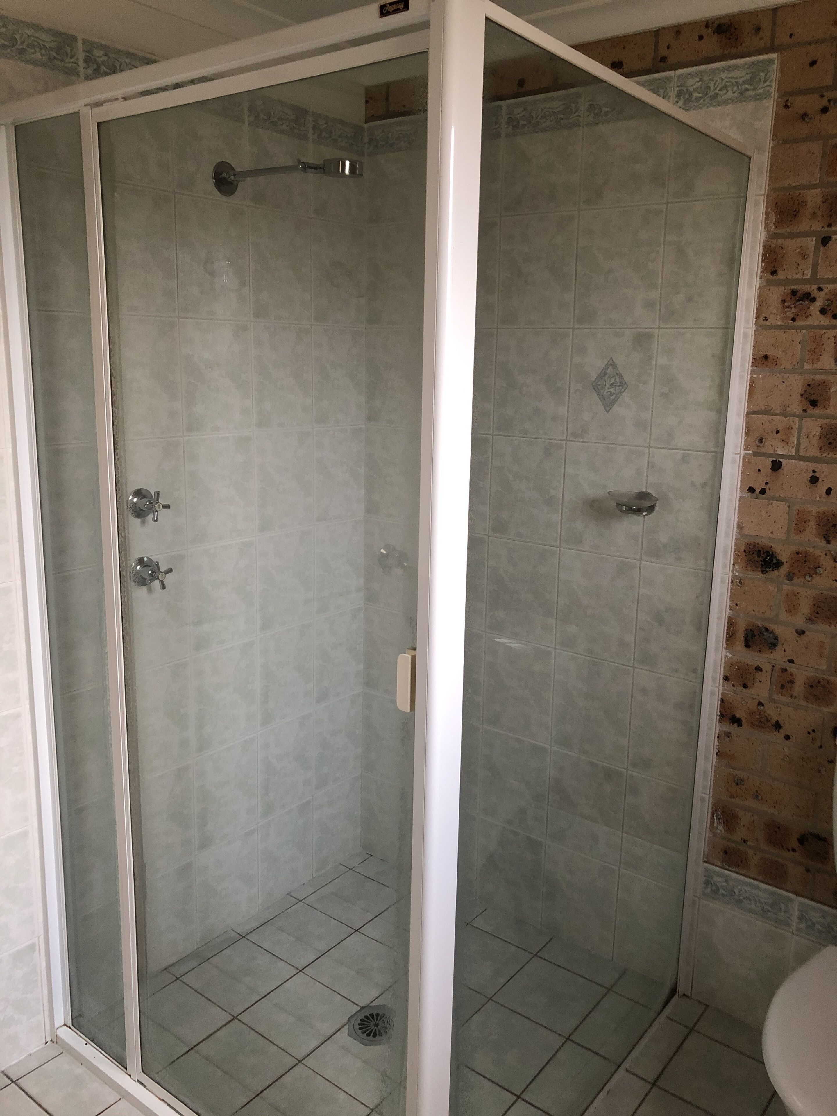 A shower with a glass door, tiled walls, and a drain.