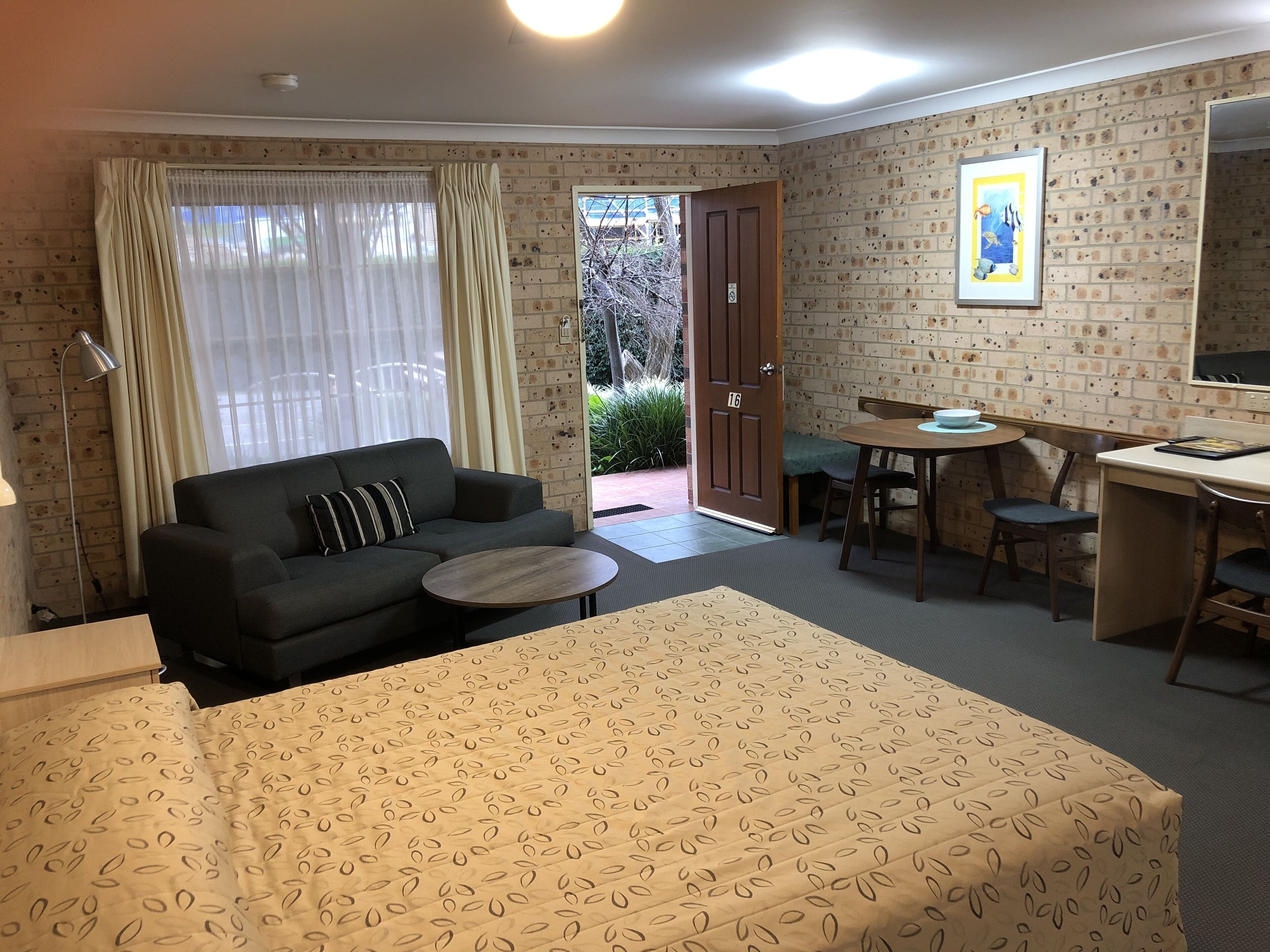 A hotel room with a bed, a sofa, a desk, and a dining table.