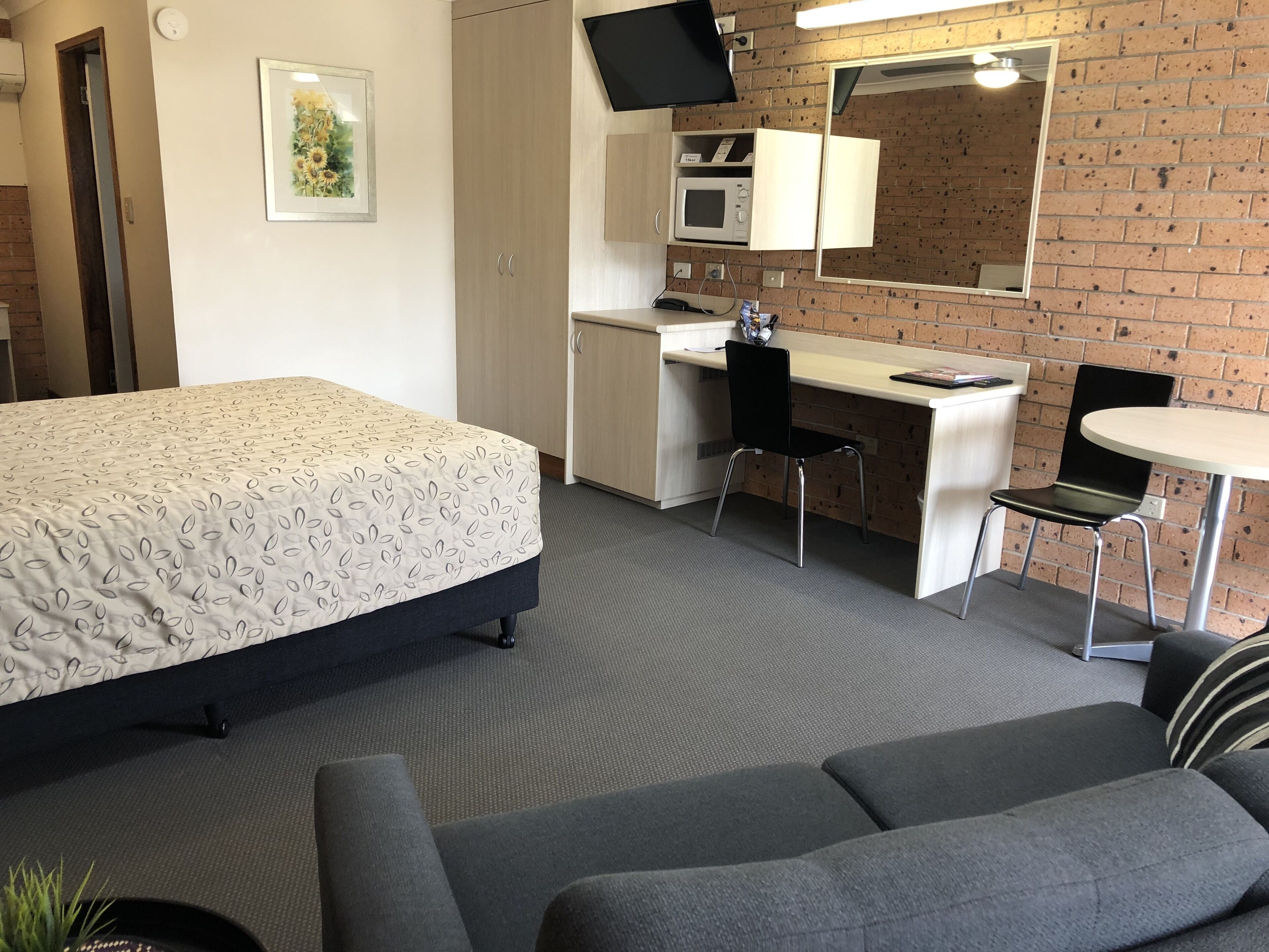 Ett hotellrum med en säng, ett skrivbord, en stol och ett litet bord.