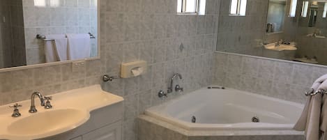Et moderne badeværelse med badekar, vask og underskab.