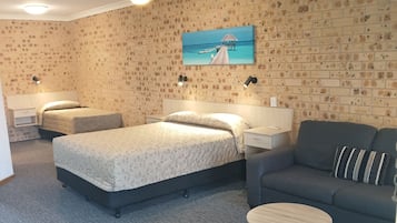 Ein Schlafzimmer mit einem Bett, einer Couch, einem kleinen runden Tisch und einer Wand mit Ziegelmuster.