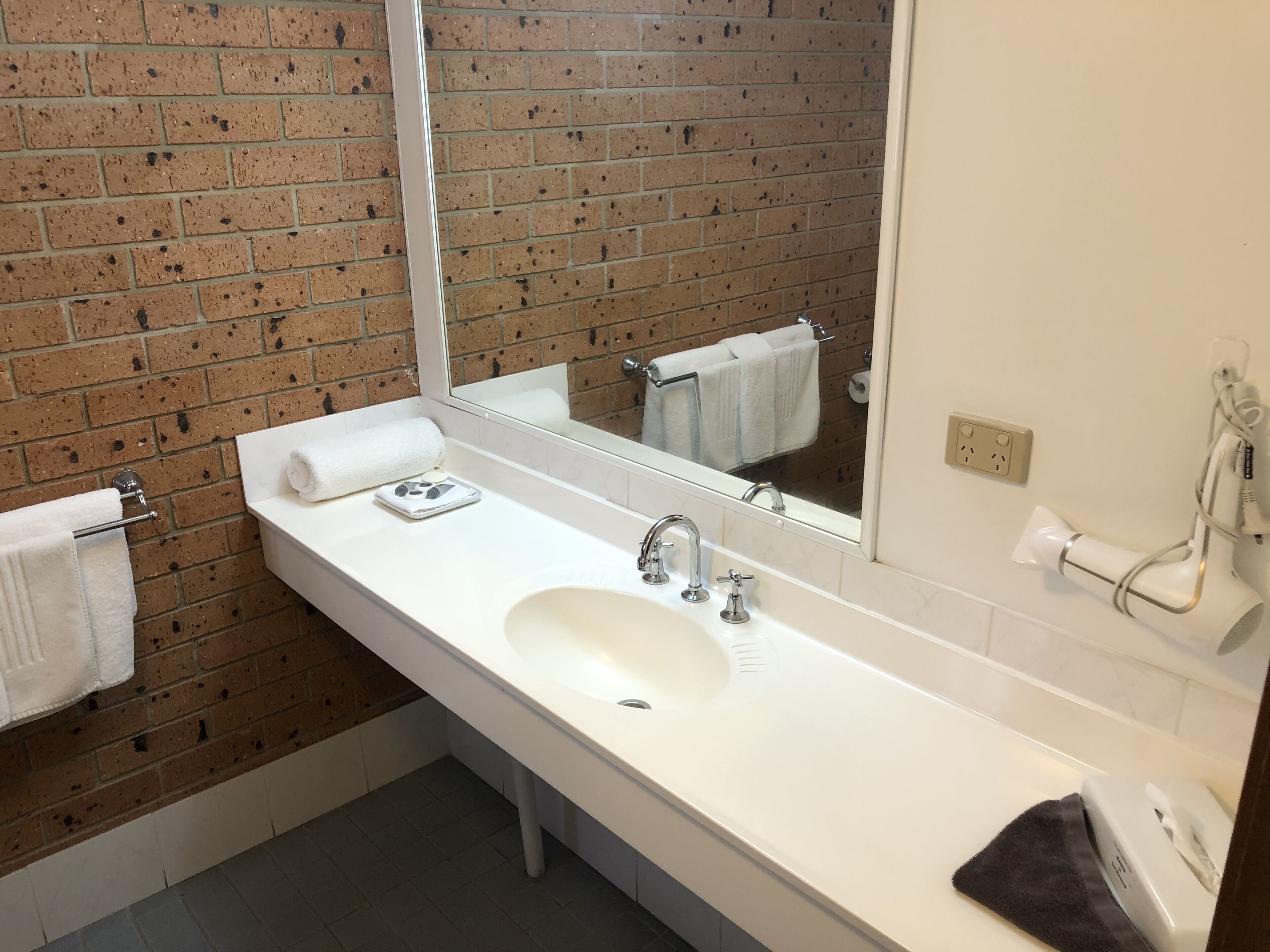 A bathroom with a white sink, a mirror, and a towel rack.