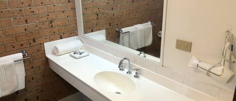 A bathroom with a white sink, a mirror, and a towel rack.