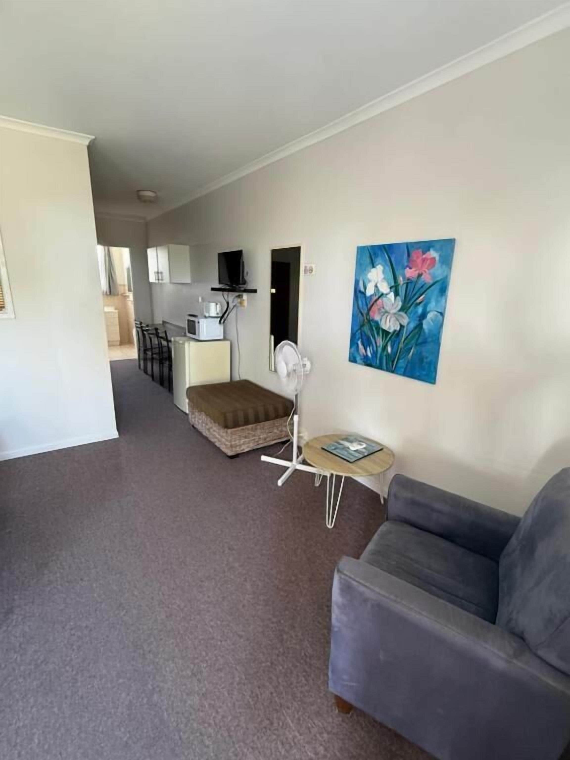 A living room with a grey sofa, a small round table, and a painting on the wall.