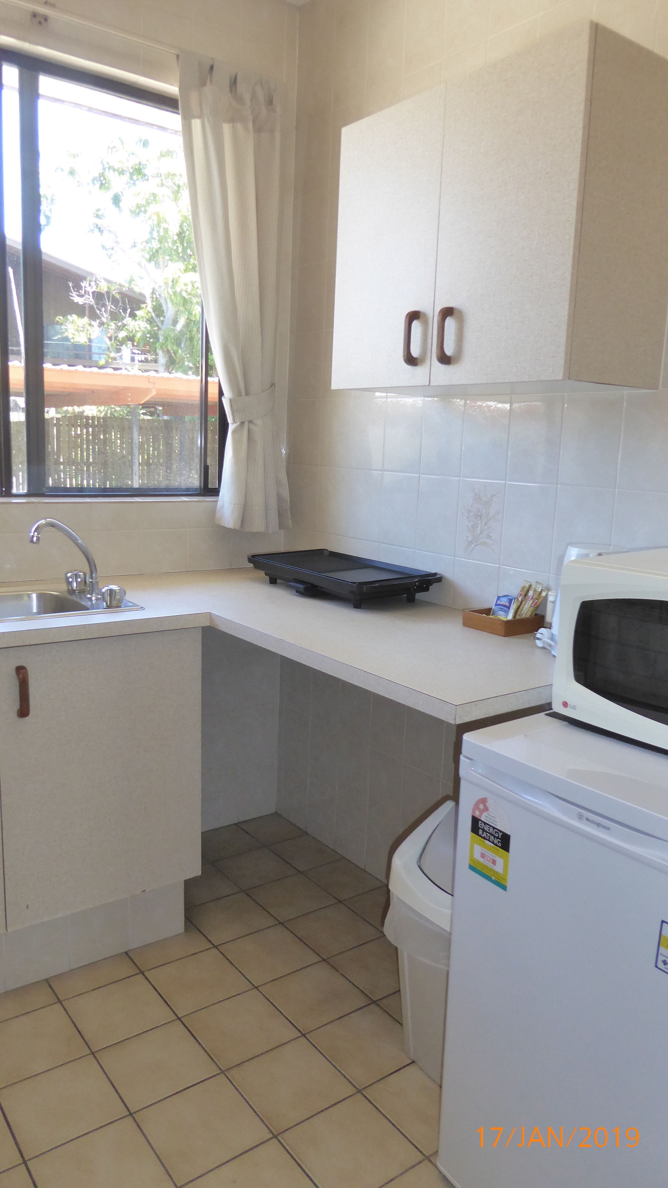 A compact kitchen with a sink, a microwave, and a small refrigerator.