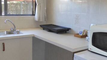 A compact kitchen with a sink, a microwave, and a small refrigerator.