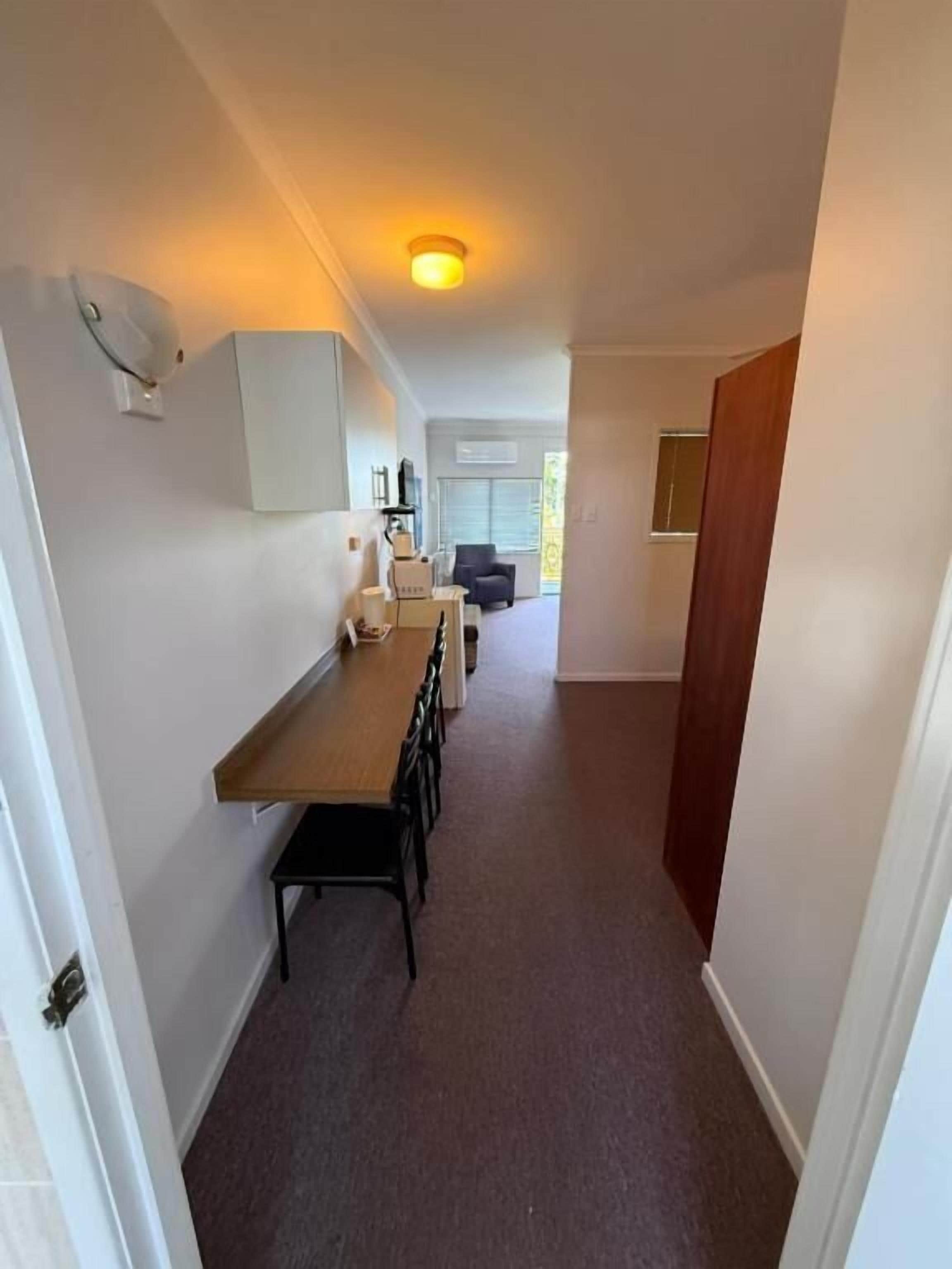 A narrow hallway with a wooden bench and a white cabinet.