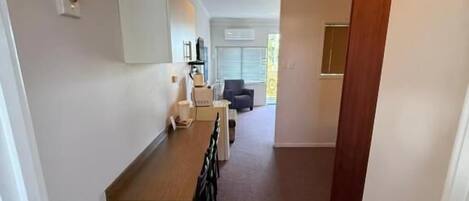 A narrow hallway with a wooden bench and a white cabinet.