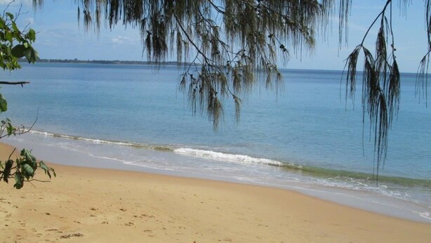 A beach with clear water, a sandy shore, and some rocks in the foreground. - Tower Court Motel (Torquay)