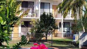 A two-story building with balconies, a swimming pool, and tropical plants. - Tower Court Motel (Torquay)
