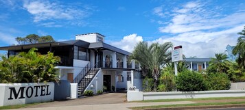 Un motel moderno con una escalera que conduce a la entrada, rodeado de abundante vegetación y palmeras.