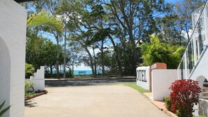 A hotel entrance with a concrete driveway leading to a covered area, surrounded by lush greenery and trees. - Tower Court Motel (Torquay)