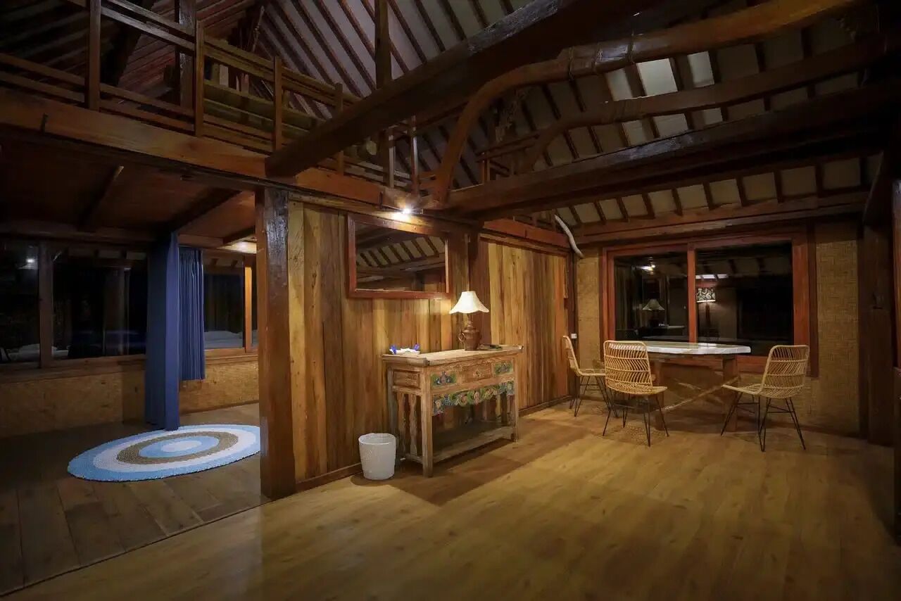 A rustic wooden interior with a dining area, a wooden cabinet, and a window.