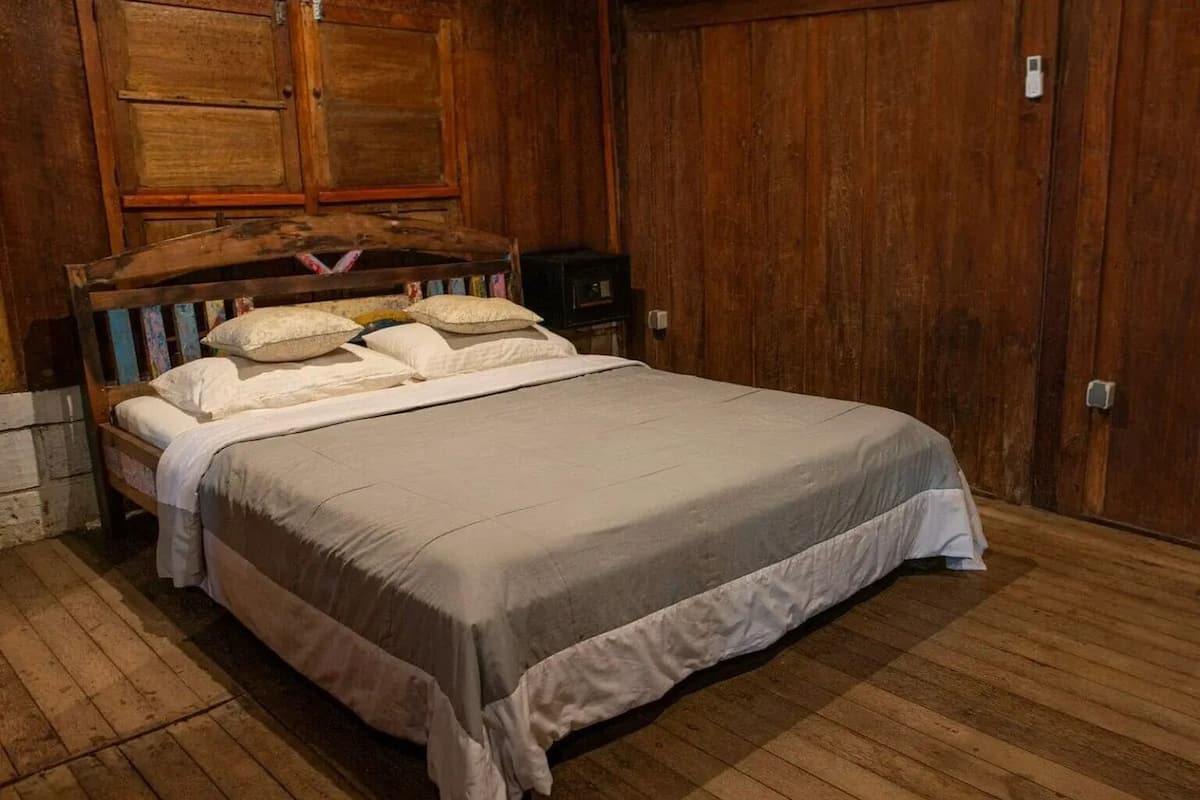 A single bed with a wooden headboard, white bedding, and a wooden floor.