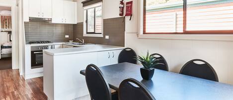 A modern kitchen with white cabinets, a central island, and a dining area with black chairs.