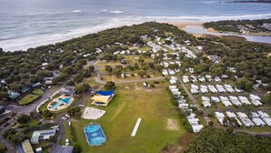 Luftaufnahme eines Campingplatzes mit Wohnmobilen, einem Schwimmbad und einem Strand.