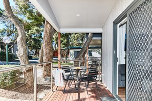Eine Terrasse im Freien mit Tisch und Stühlen, umgeben von Bäumen und einem Zaun.