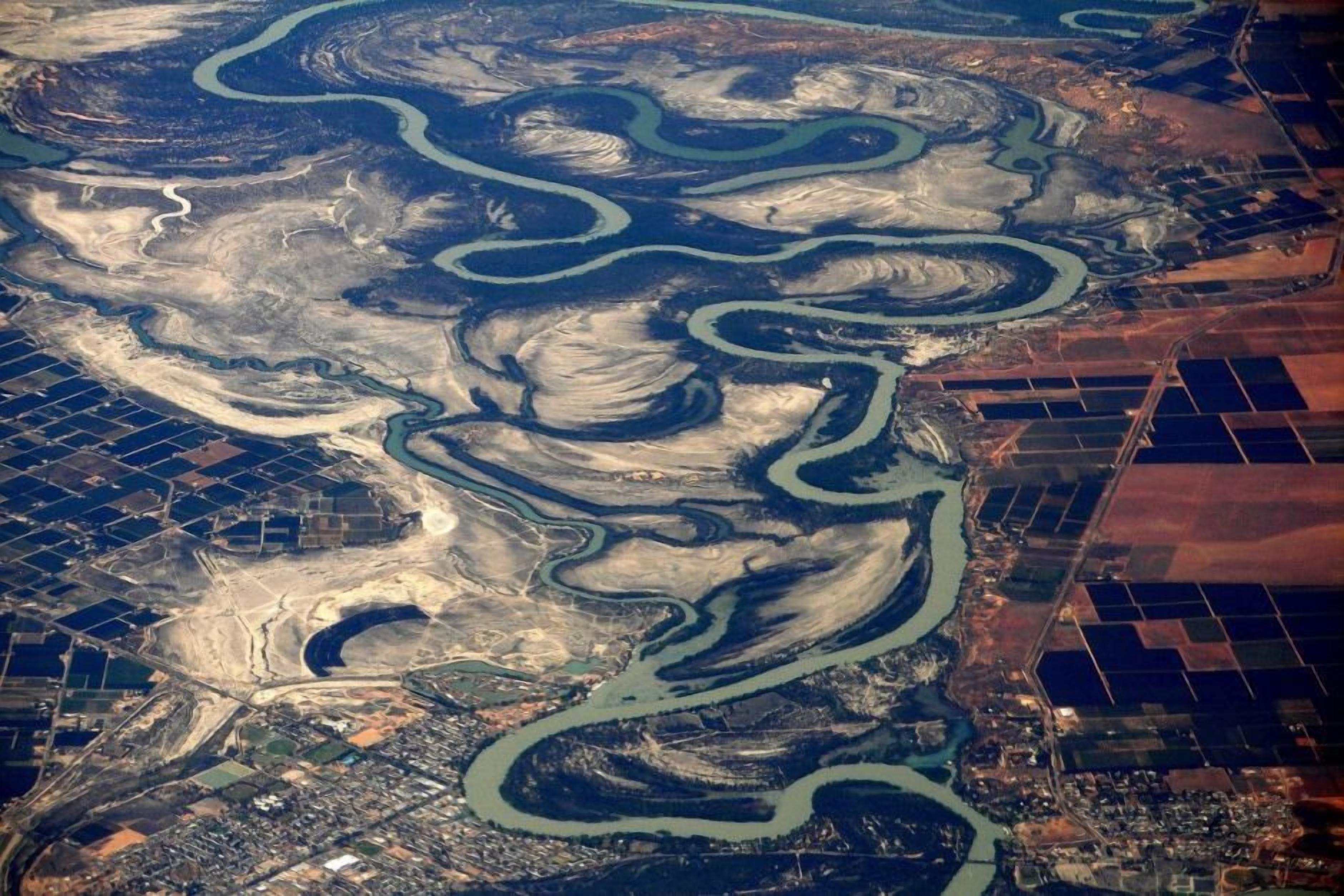 An aerial view of a mining area with winding water channels and industrial structures.