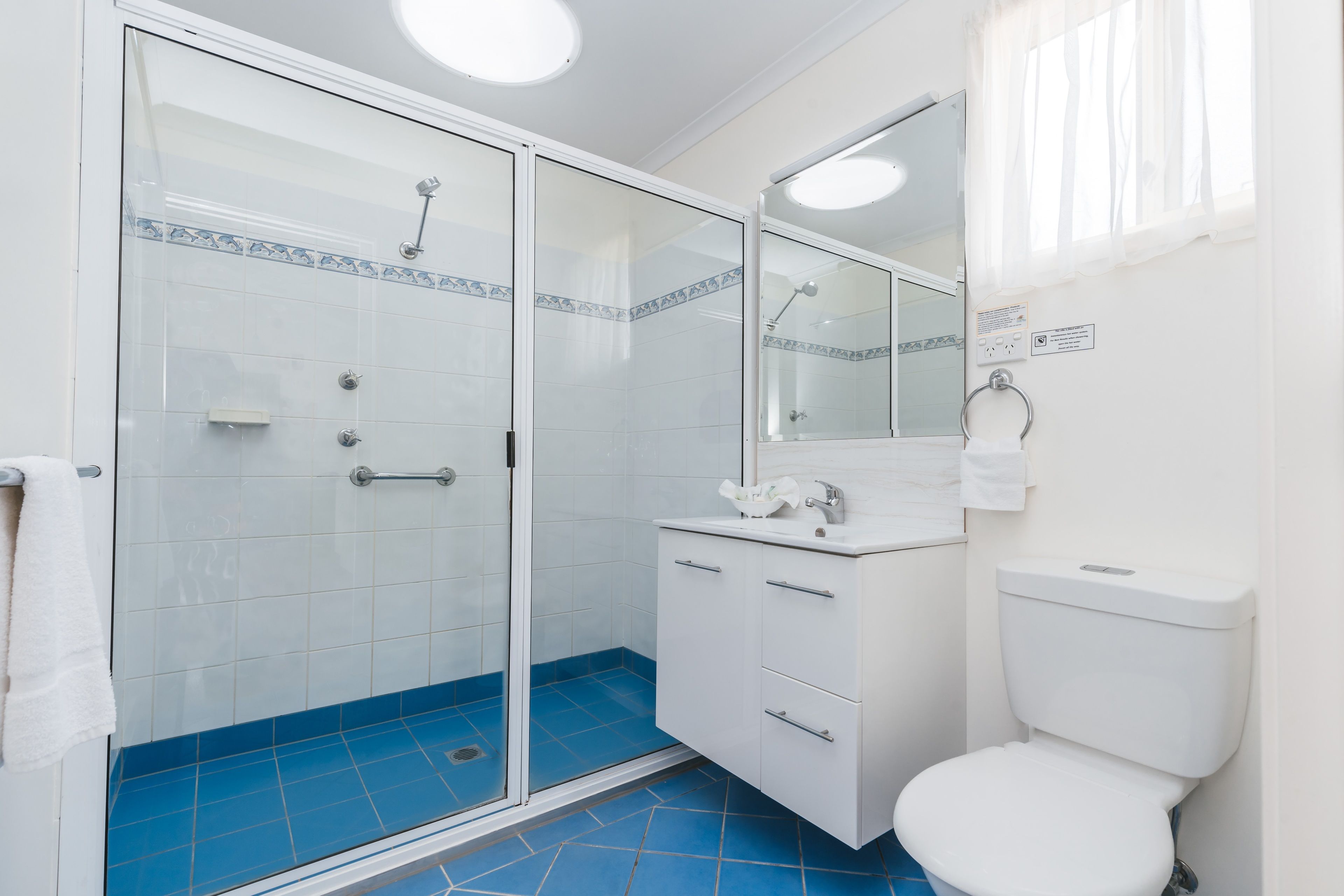 Une salle de bain avec une douche à parois de verre, un lavabo blanc et des toilettes.