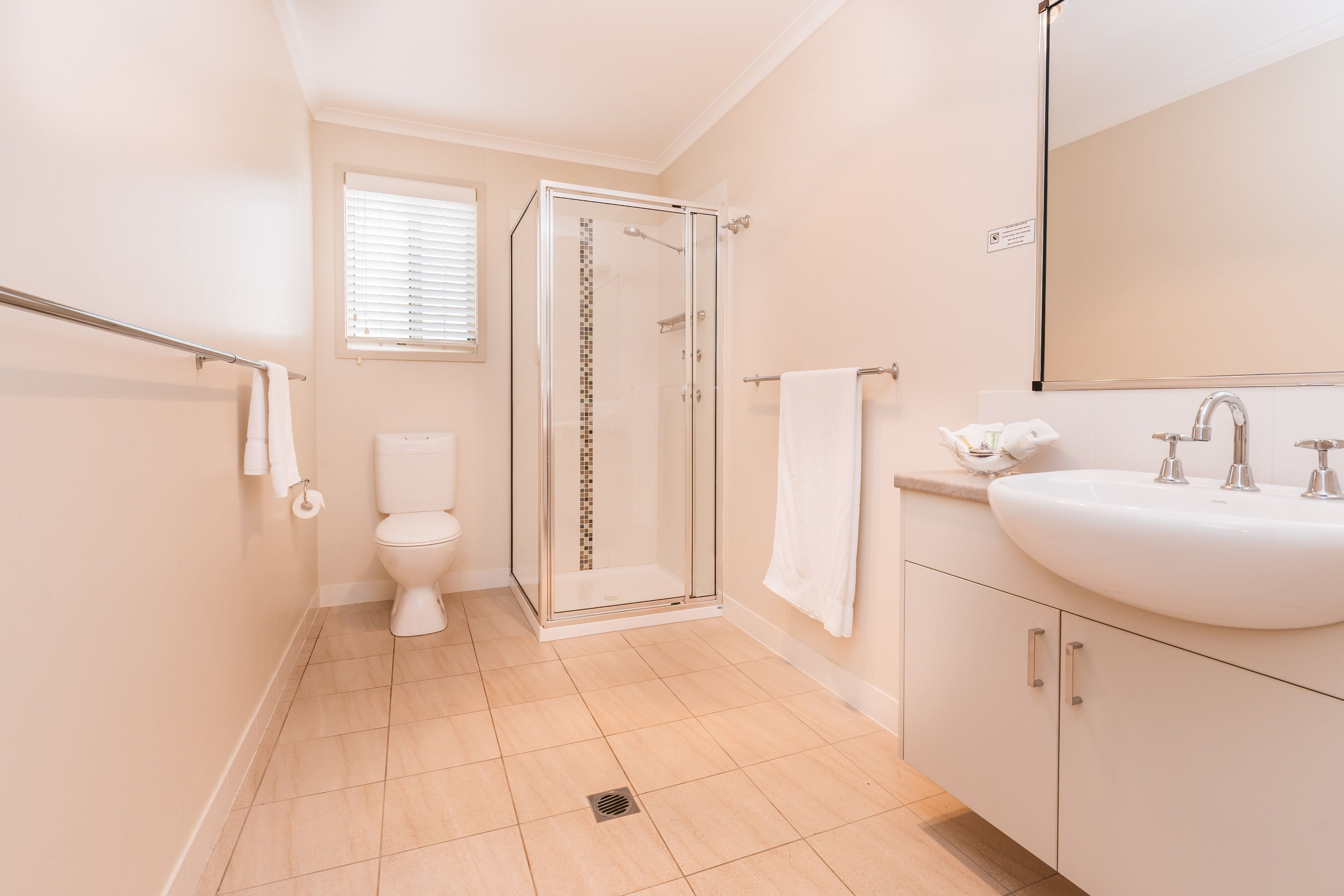 A modern bathroom with a glass-enclosed shower, a white sink, and a toilet.