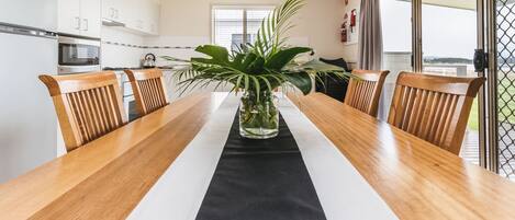 Una cocina moderna con armarios blancos, una mesa de comedor de madera con un mantel negro y una planta en maceta.