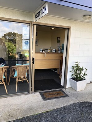 A reception area with a sign, a counter, a computer, and a potted plant. - Waiheke Island Motel (Waiheke Island)