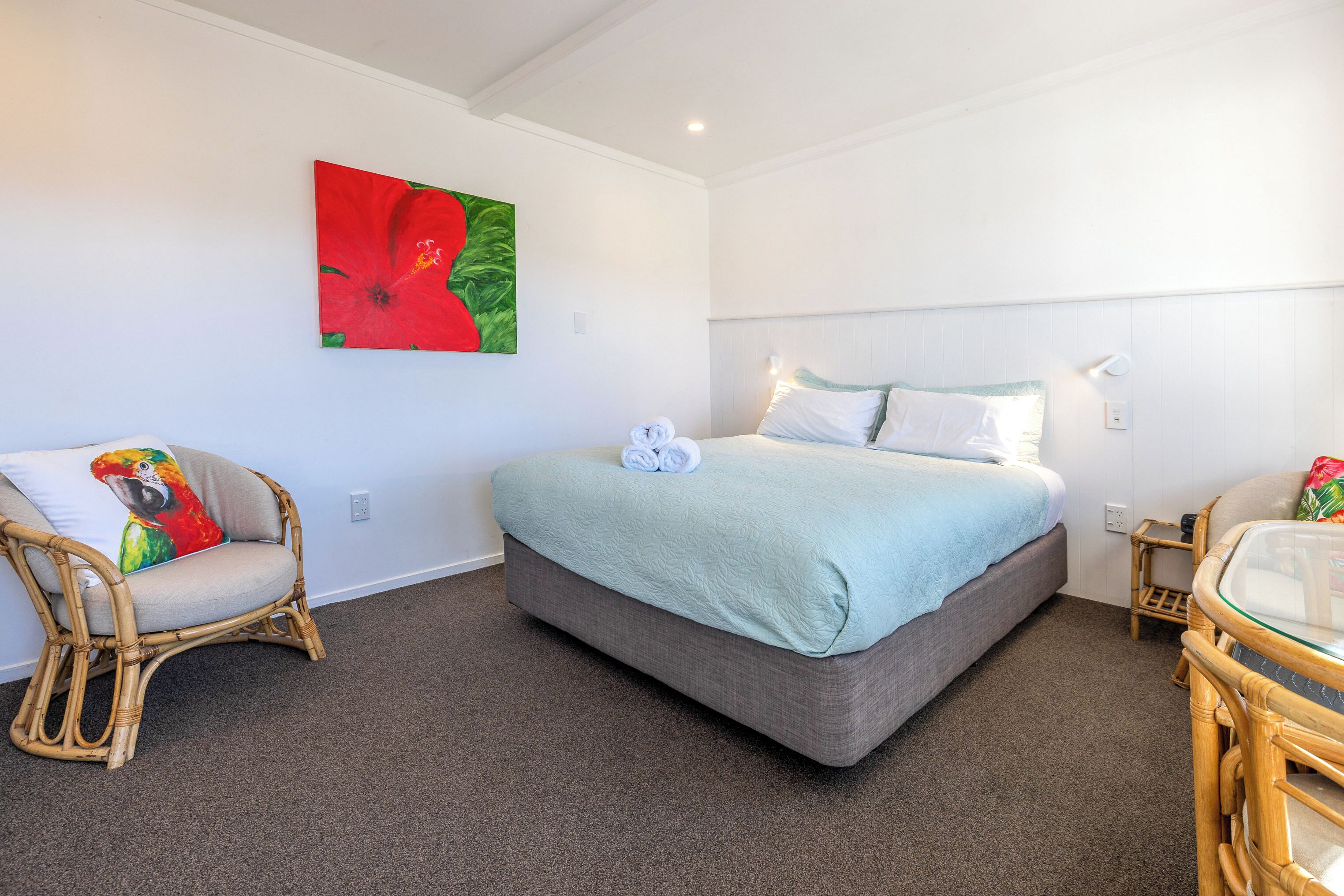 Quarto com cama, uma cadeira, uma mesa e um quadro na parede.