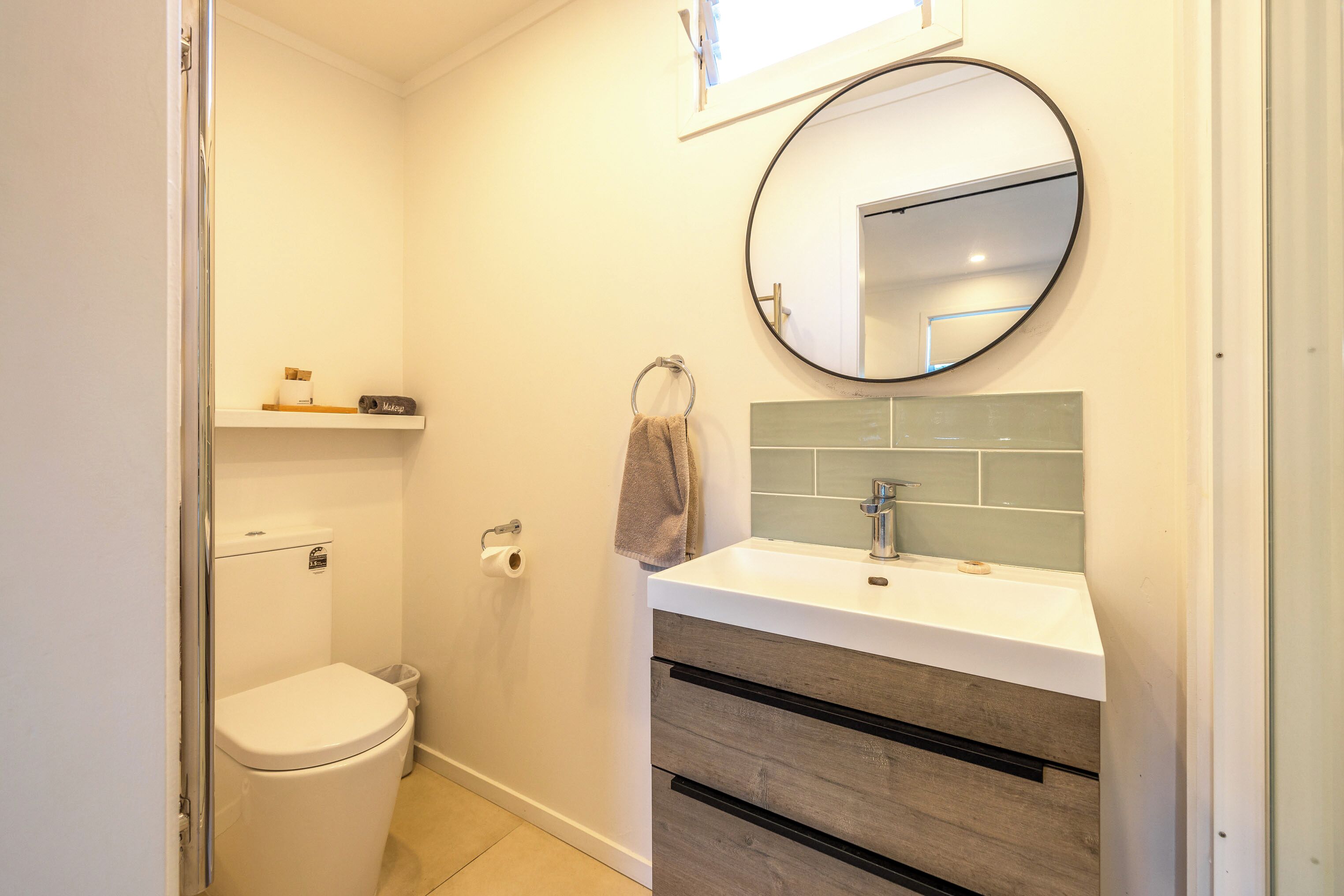 A modern bathroom with a toilet, sink, and mirror.