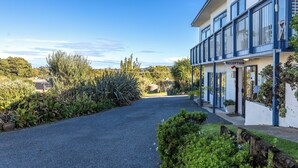 A building with a reception area, surrounded by greenery and a gravel path. - Waiheke Island Motel (Waiheke Island)