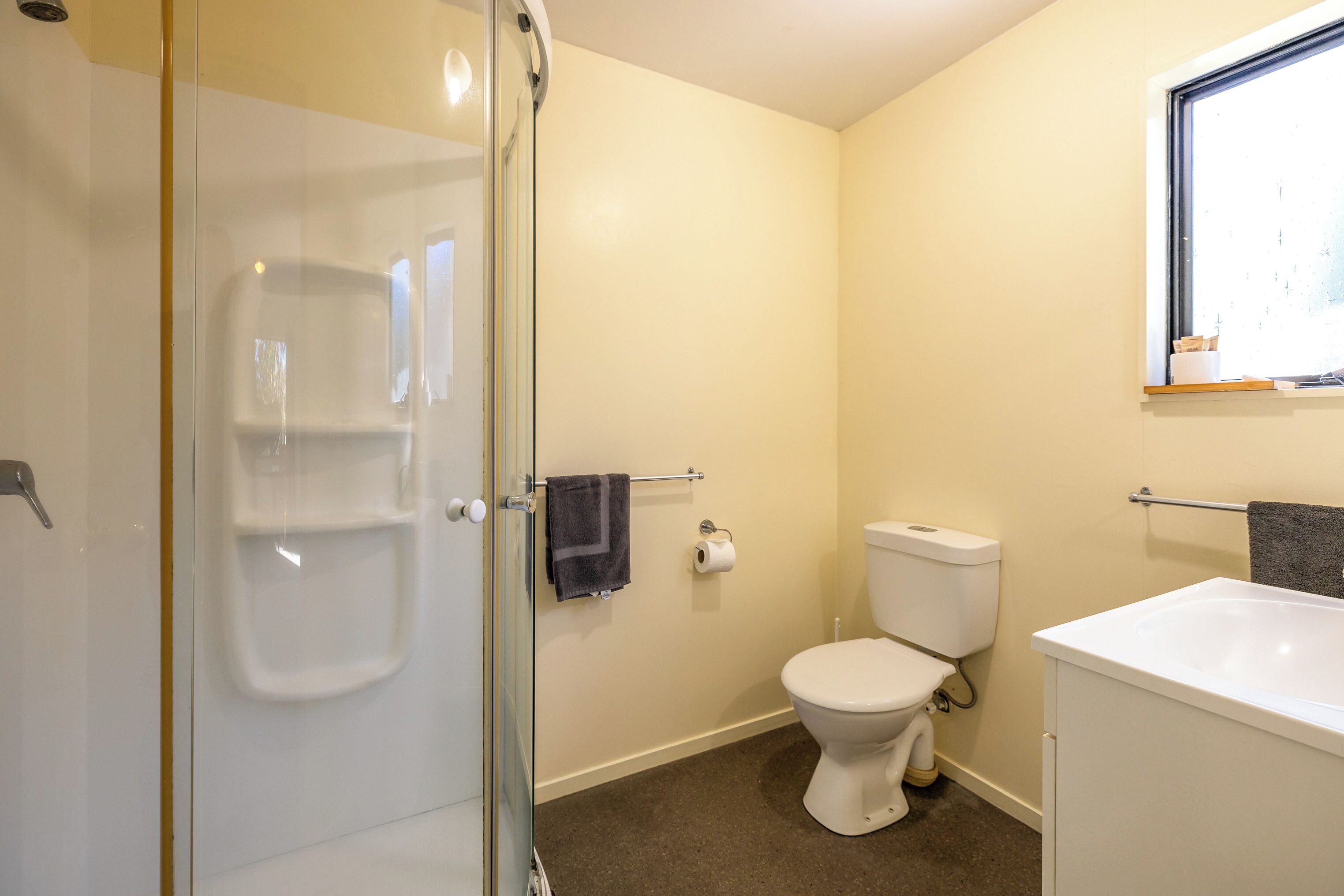 A bathroom with a glass shower enclosure, a toilet, and a sink.