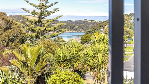 A view from a window overlooking a lake, surrounded by lush greenery and hills. - Waiheke Island Motel (Waiheke Island)