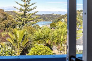 Vista desde una ventana sobre un lago, rodeado de abundante vegetación y colinas.