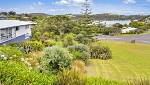 A motel with a white exterior, surrounded by lush greenery and a view of a lake and hills. - Waiheke Island Motel (Waiheke Island)