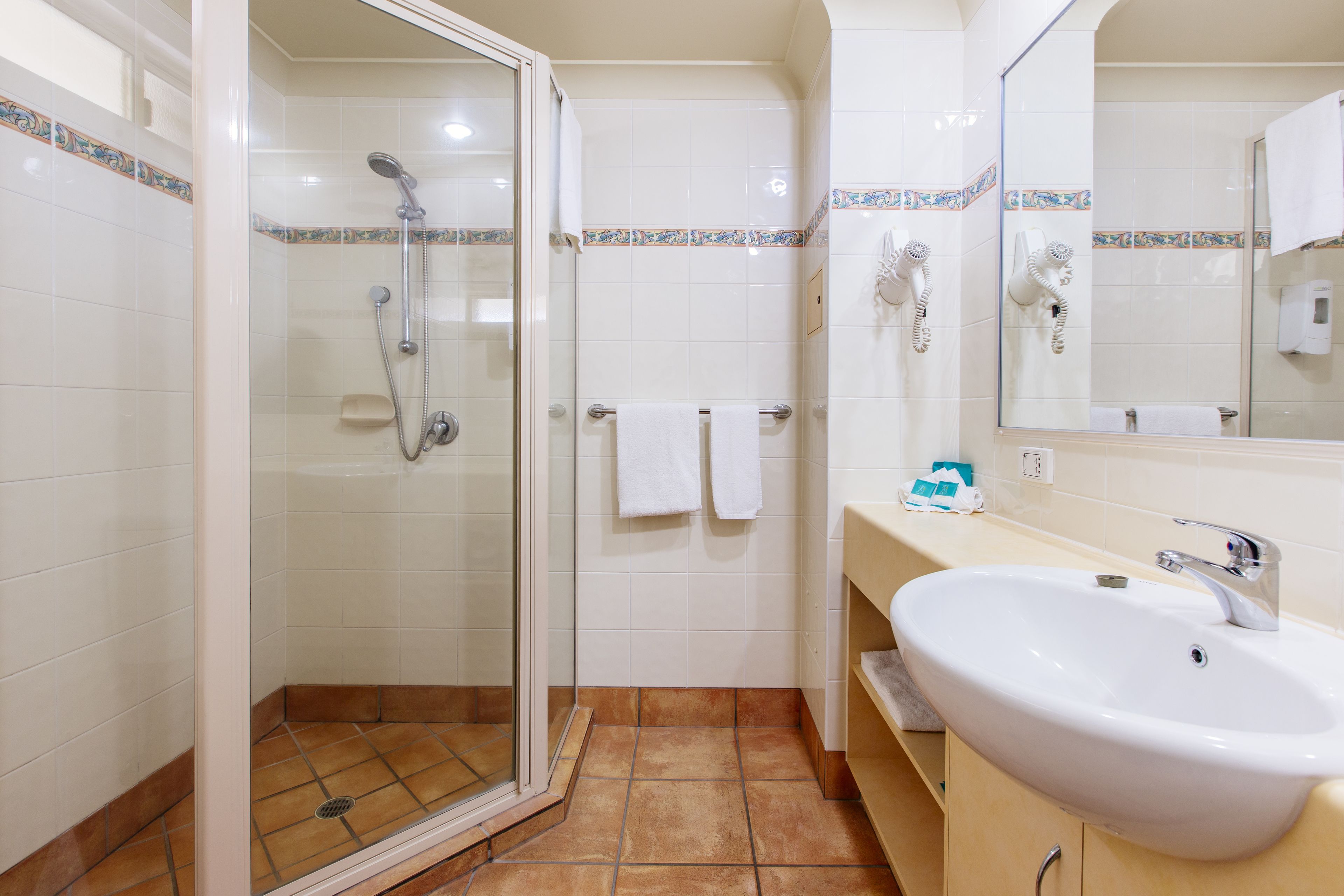 Een badkamer met een douche met glazen wand, een wastafel en een spiegel.