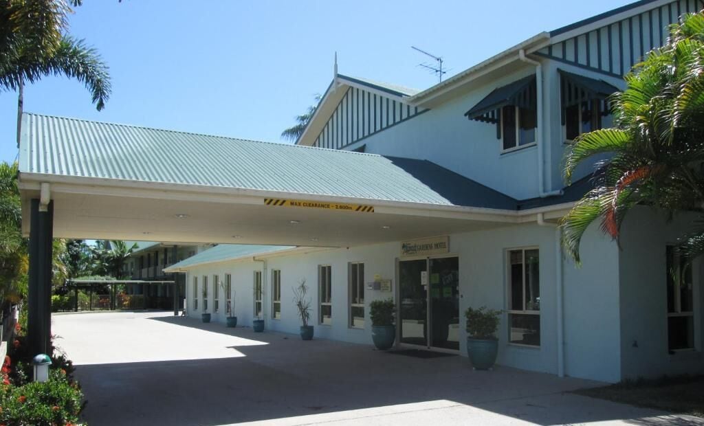 A hotel with a covered entrance, a sign indicating a 3,000m clearance, and a sign for the "Coconut Grove Hotel".