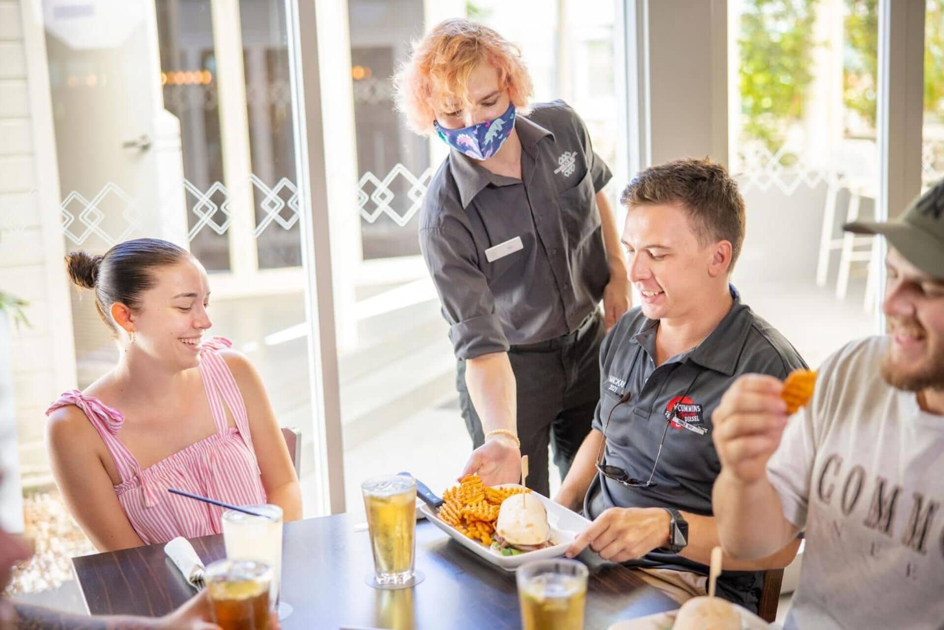 Un grupo de personas cenando en un restaurante con un amplio ventanal al fondo.