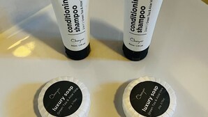 Two tubes of shampoo and two soap bars on a white surface. - Beenleigh Village Motel (Beenleigh)