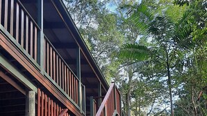 A wooden staircase leading to a balcony with a view of a forested area. - Treetops Accommodation Montville (Flaxton)