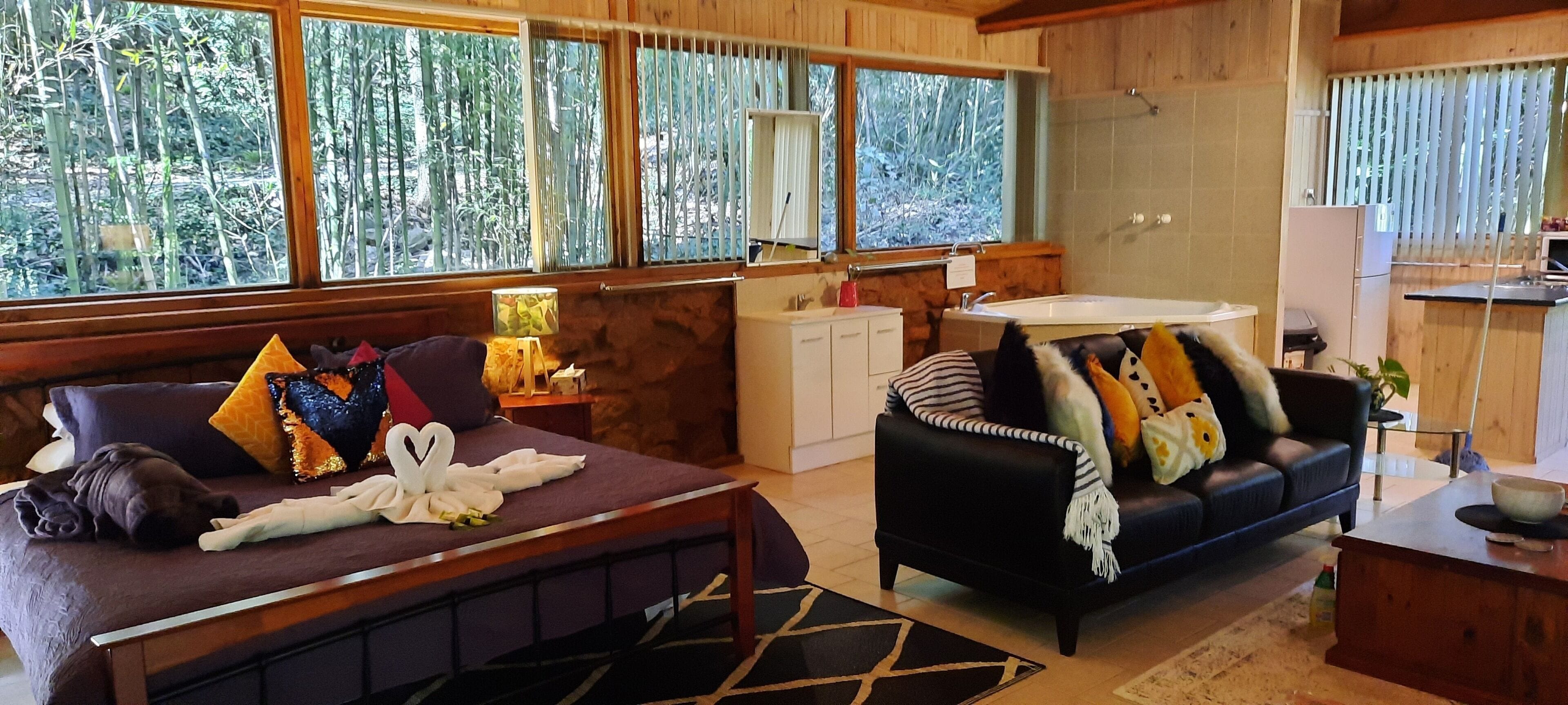 A cozy room with a bed, a sofa, and a small kitchen area.