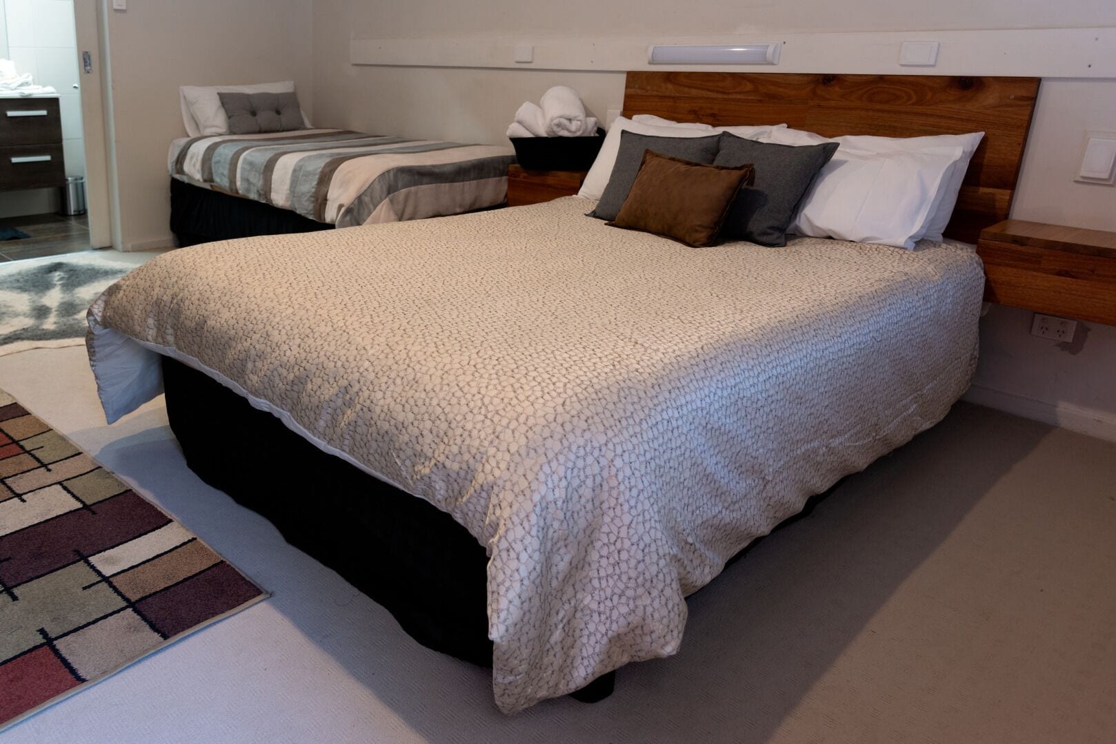 A bedroom with a large bed, a nightstand, a wooden headboard, and a bedside table.