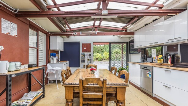 Una cocina con una mesa de comedor de madera, armarios blancos y un horno empotrado.