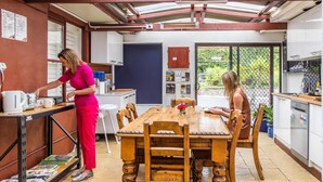 Una cocina con una mesa y sillas de madera, una cafetera y un refrigerador.