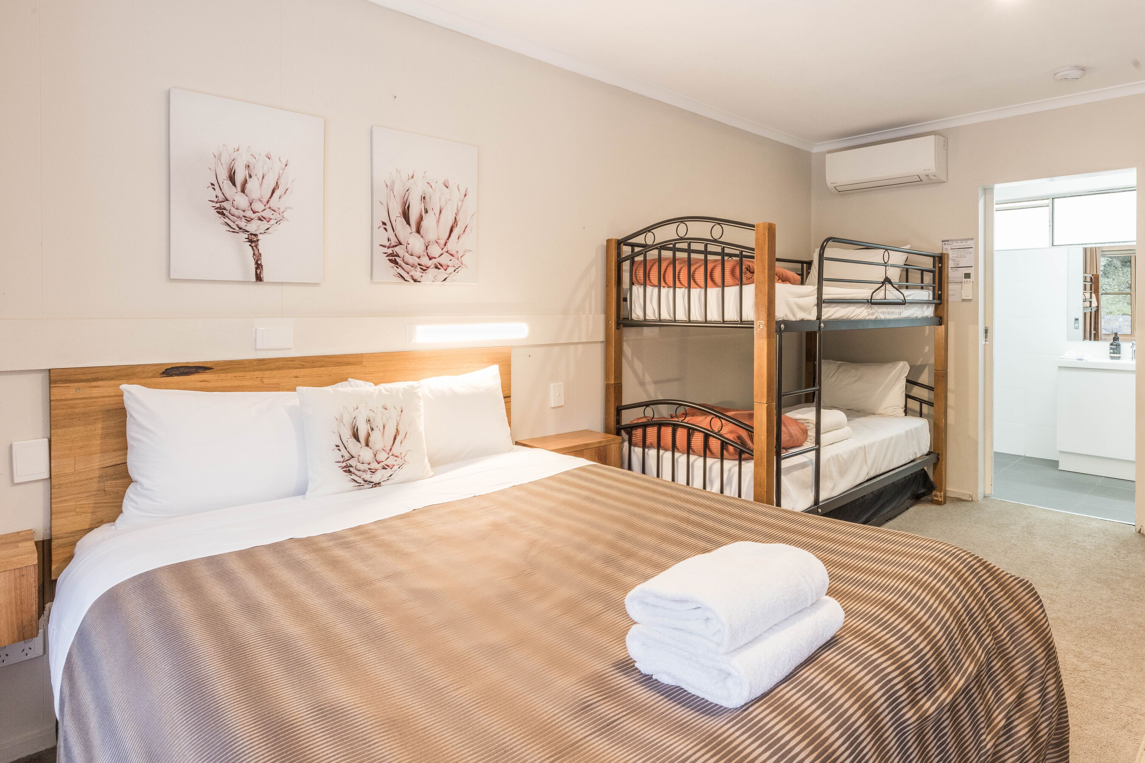 A hotel room with a large bed, bunk beds, and artwork on the walls.