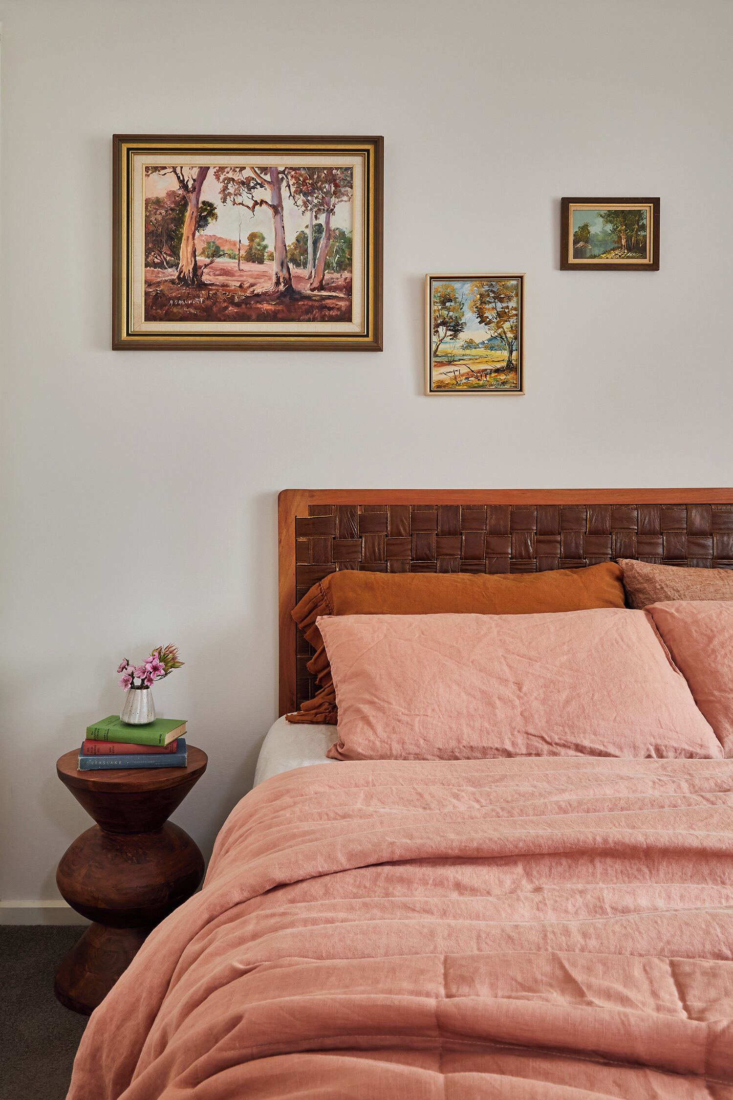 Un dormitorio con una cama grande, un cabecero de madera y dos cuadros enmarcados en la pared.
