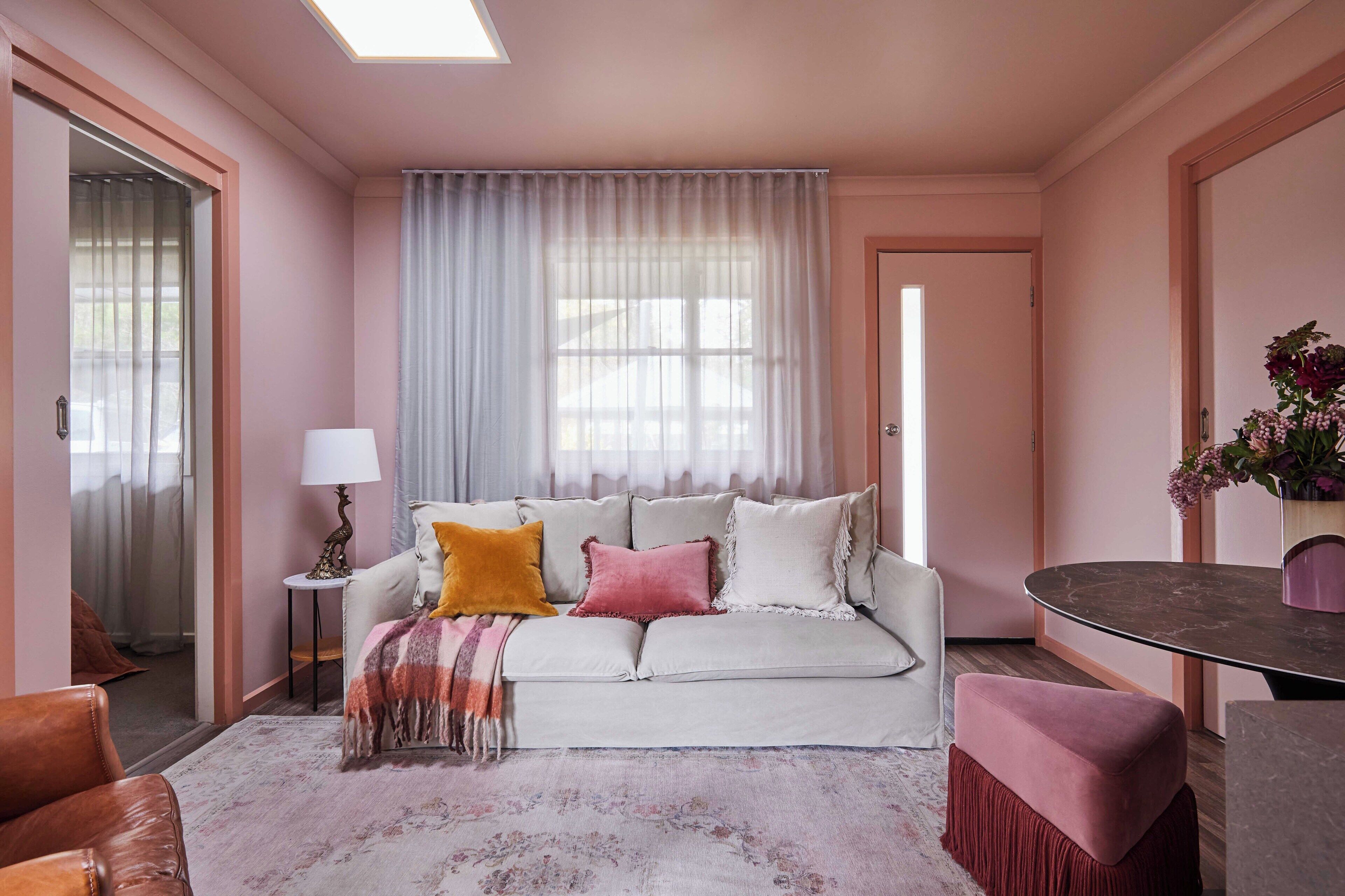 Un salon avec un canapé, une table, une lampe et une fenêtre avec des rideaux.