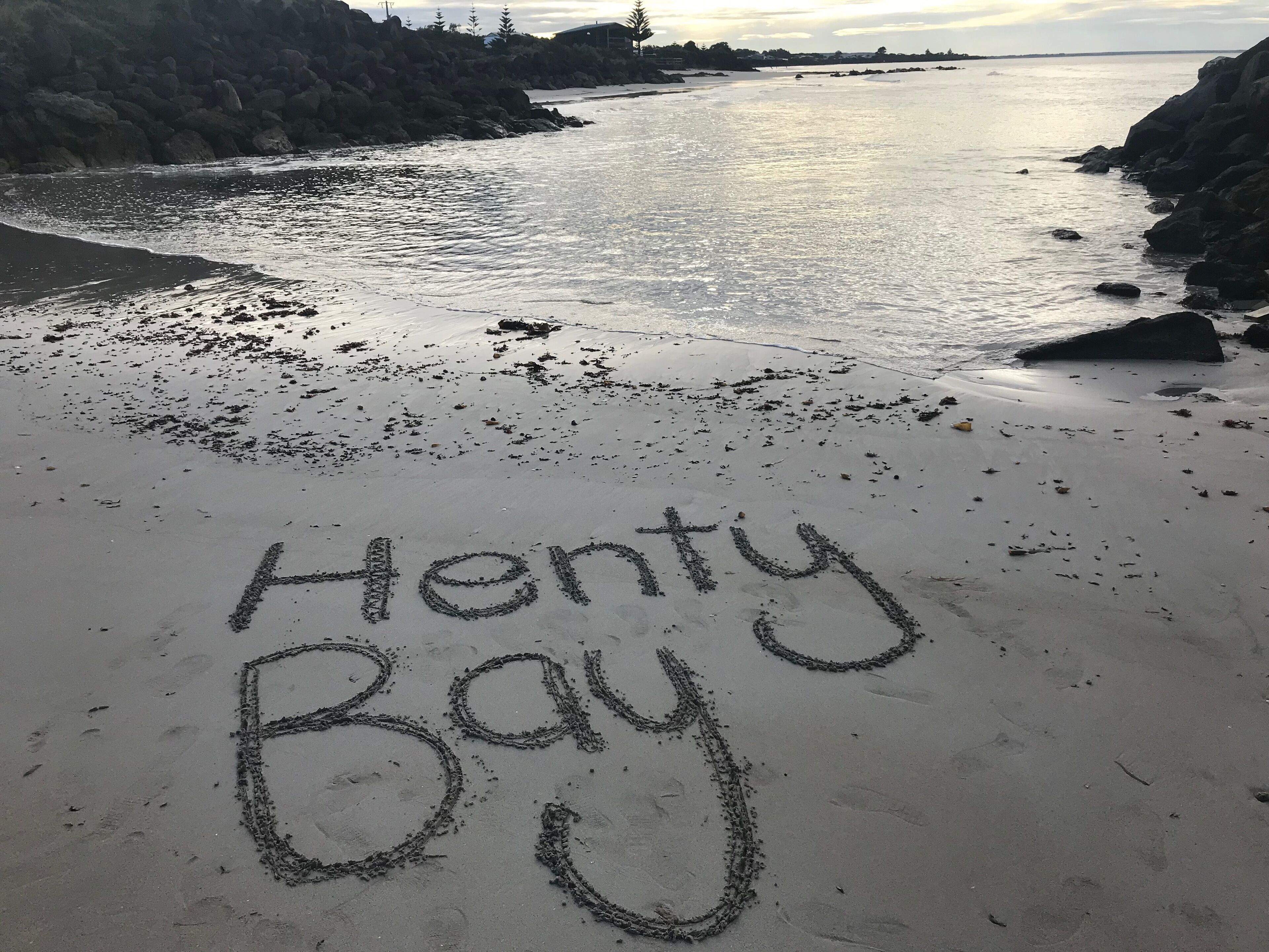 A beach with the words "Henty Bay" written in the sand.